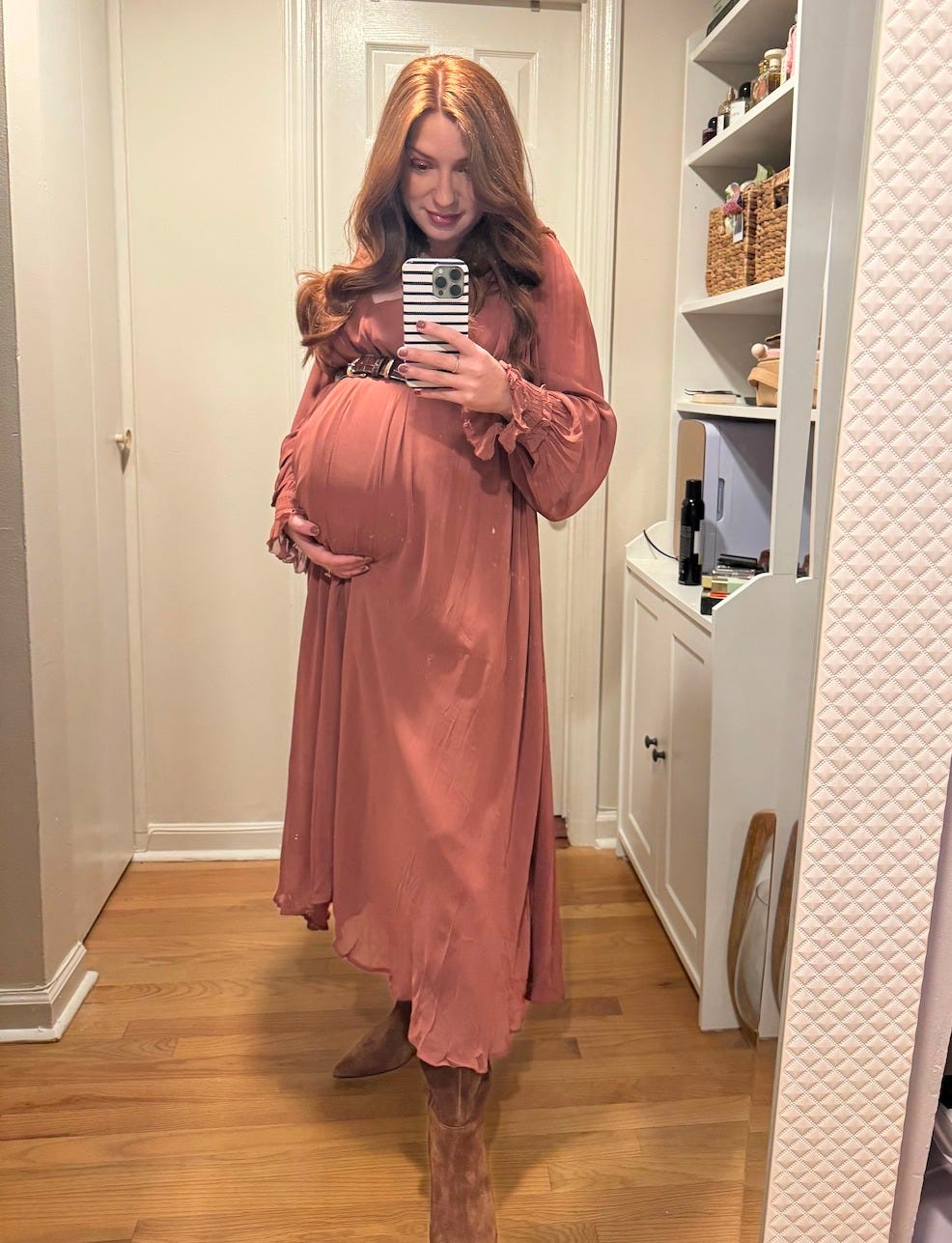 pregnant Kassidy Silva posing in front of a mirror in a long terracotta dress