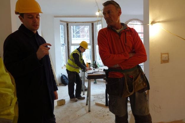 Joe from Assemble, back from Glasgow, talking with Dave the joiner, while his 16 year old apprentice Charlie works in the background.