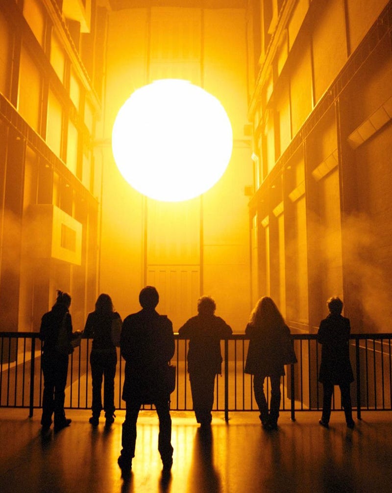 People looking  at a giant ball that looks like the sun