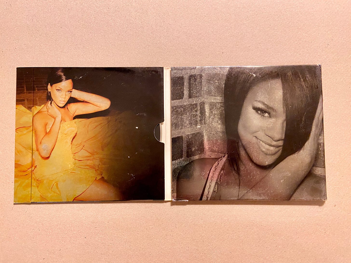 the images on the fold of the digipak CD for Rihanna's Good Girl Gone Bad image. in one photo, she wears a yellow dress with her hair slicked back; in the second b&w image, she smiles at the camera while holding her head.