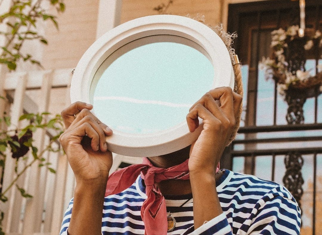 person in striped shirt holding round mirror