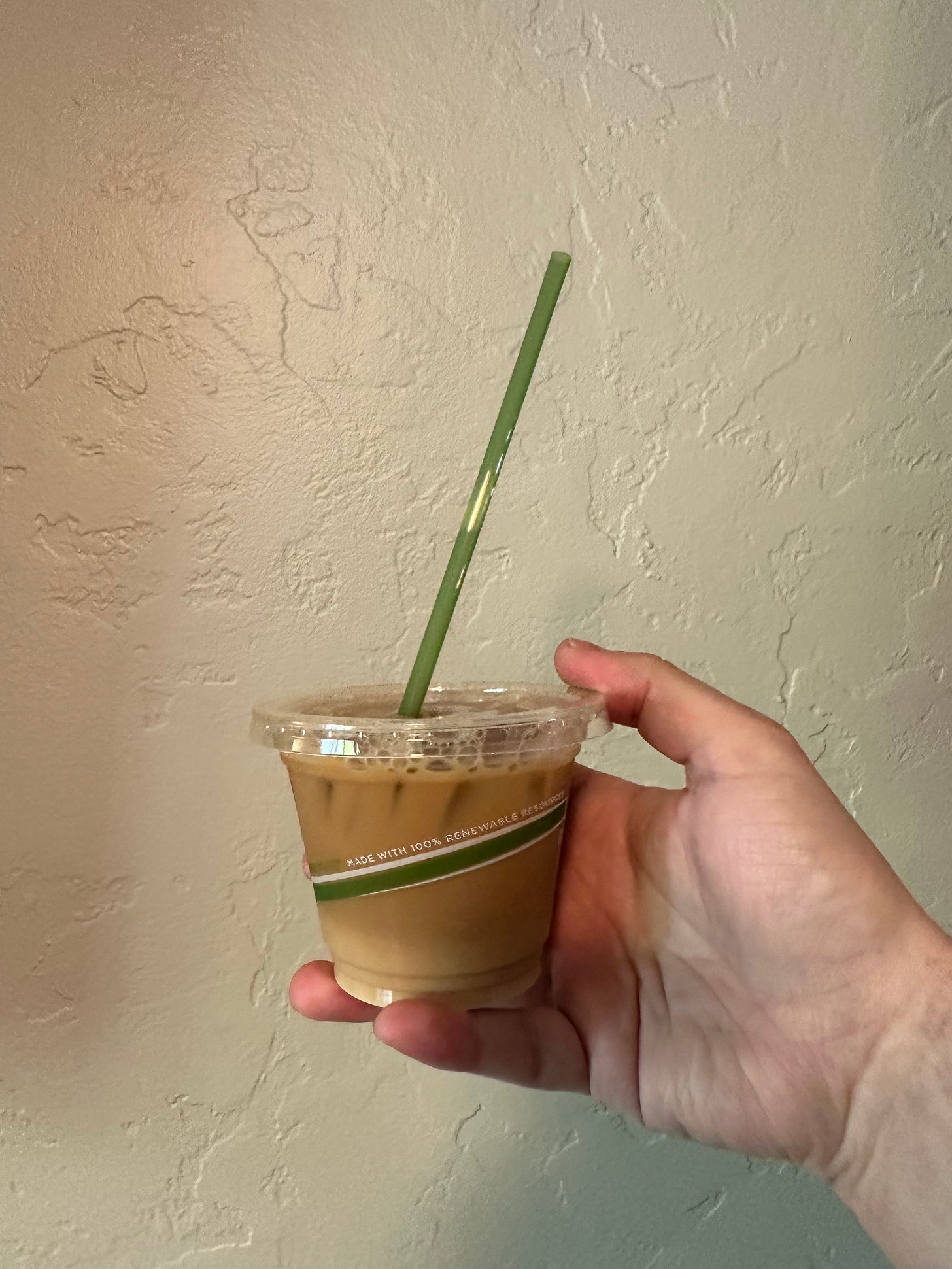 A very small coffee with a normal sized straw in my slightly small hand.