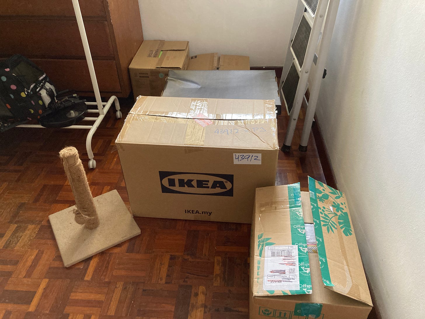 A photo of packed boxes, the bottom half of a ladder, and a white rolling clothes rack.
