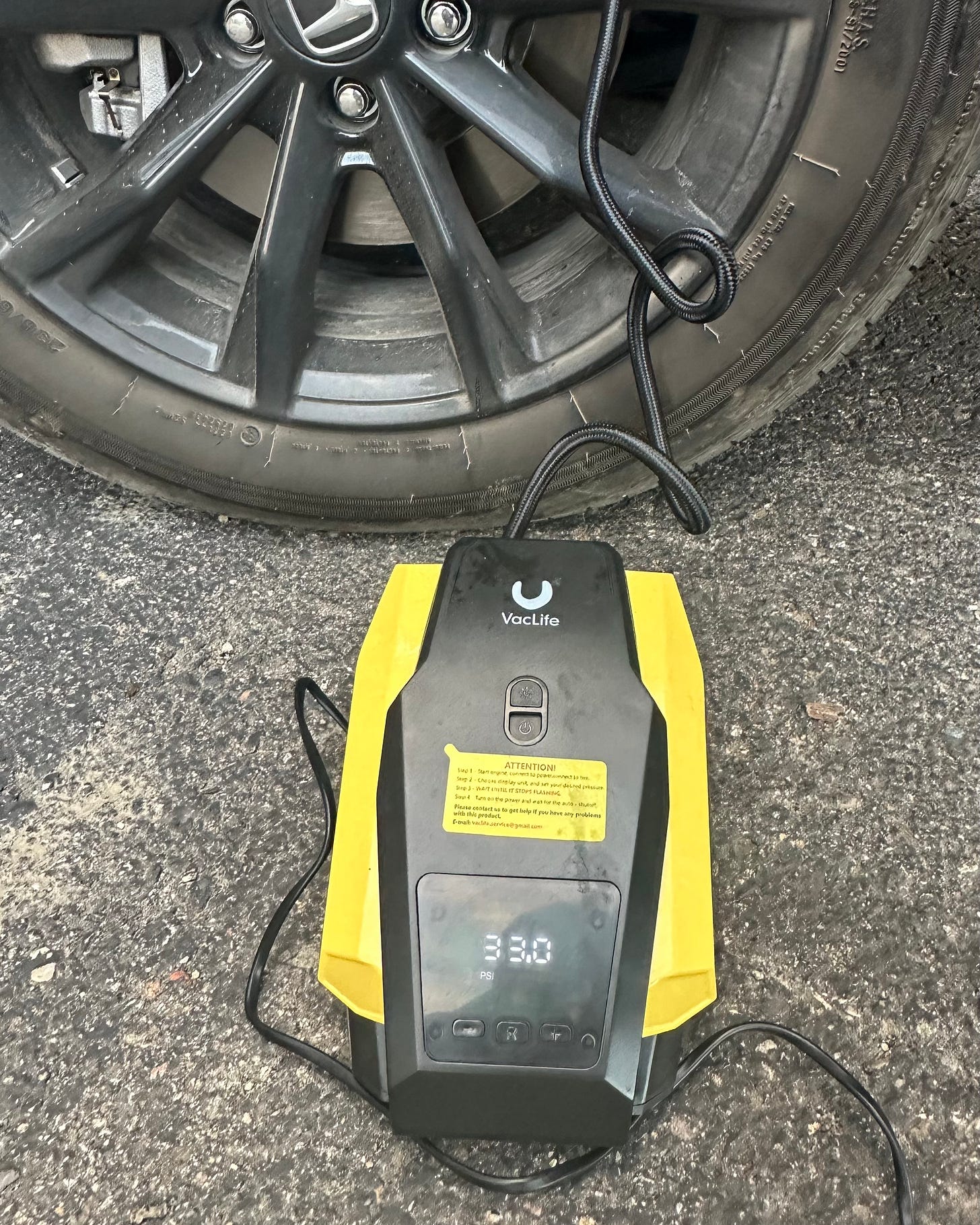 A photo of a yellow and black tire inflator connected to one of the tires of Shohreh's Honda CR-V