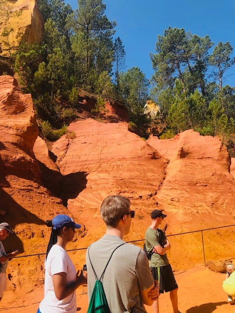 A group of people standing in front of a red rock

Description automatically generated with low confidence