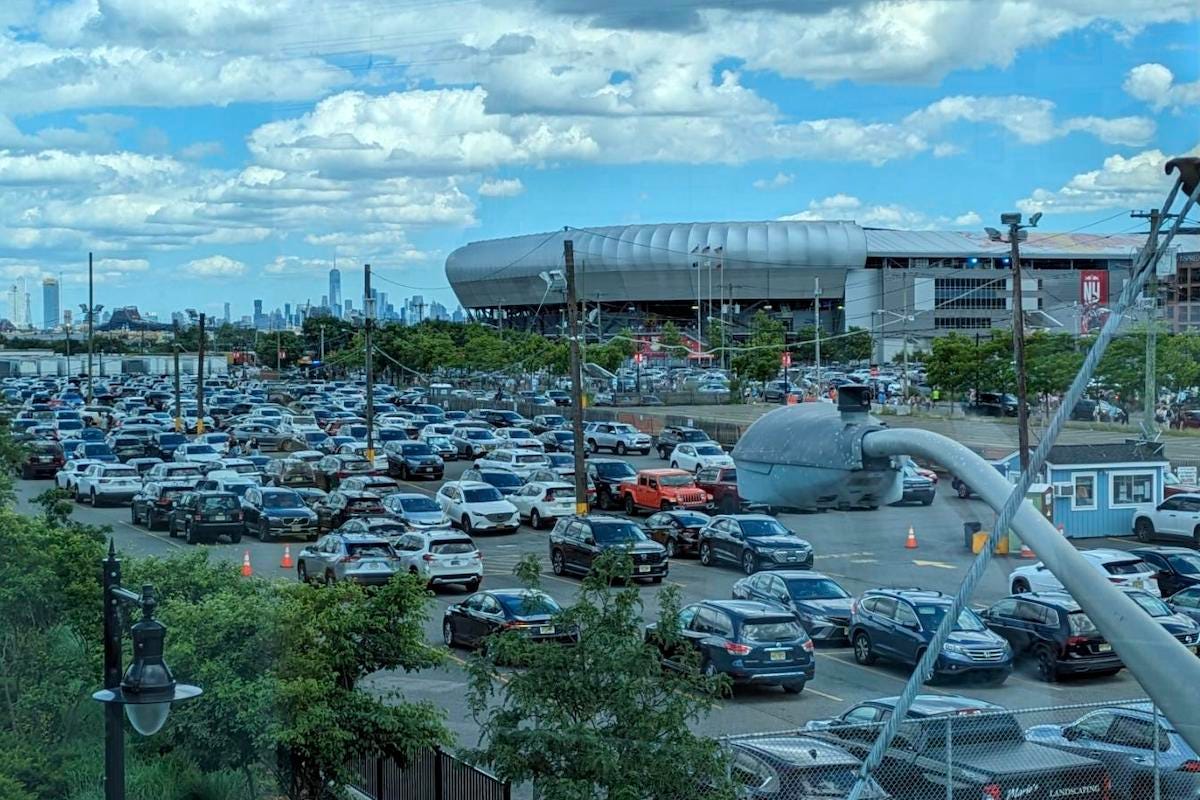 View of a parking lot, with a stadium do the right side, and the NYC skyline to the left.