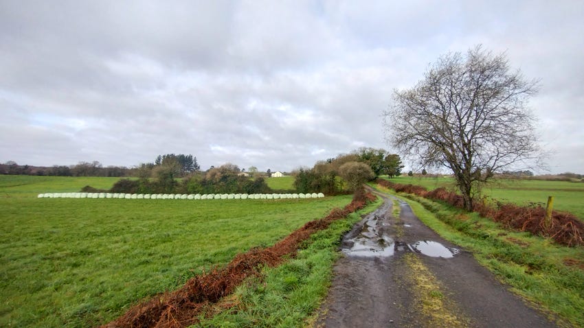 Pista entre campos con fardos de heno