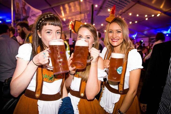 Three young women pose with beer steins