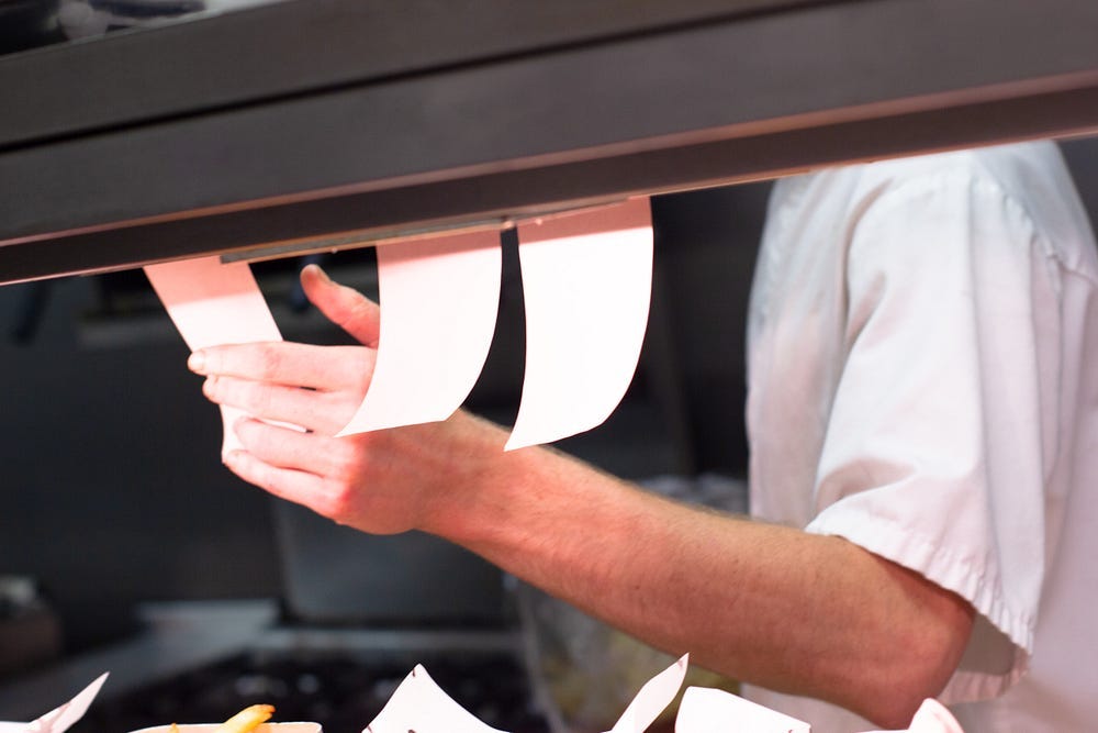 A chef in his kitchen about to grab the next order slip. For product managers, orders are synonymous with feature requests!