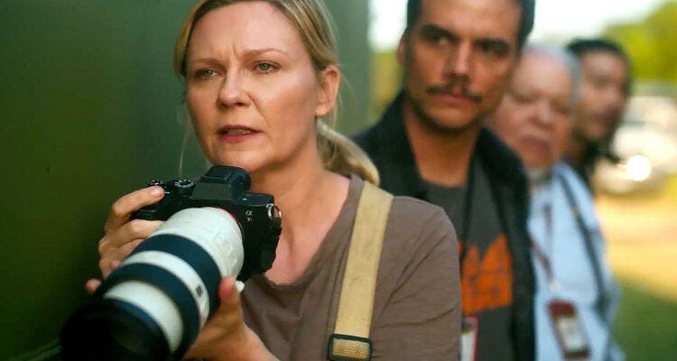 Imagem do filme Guerra Civil. Kristen Dunst está segurando uma câmera, atrás dela Wagner Moura aparece desfocado