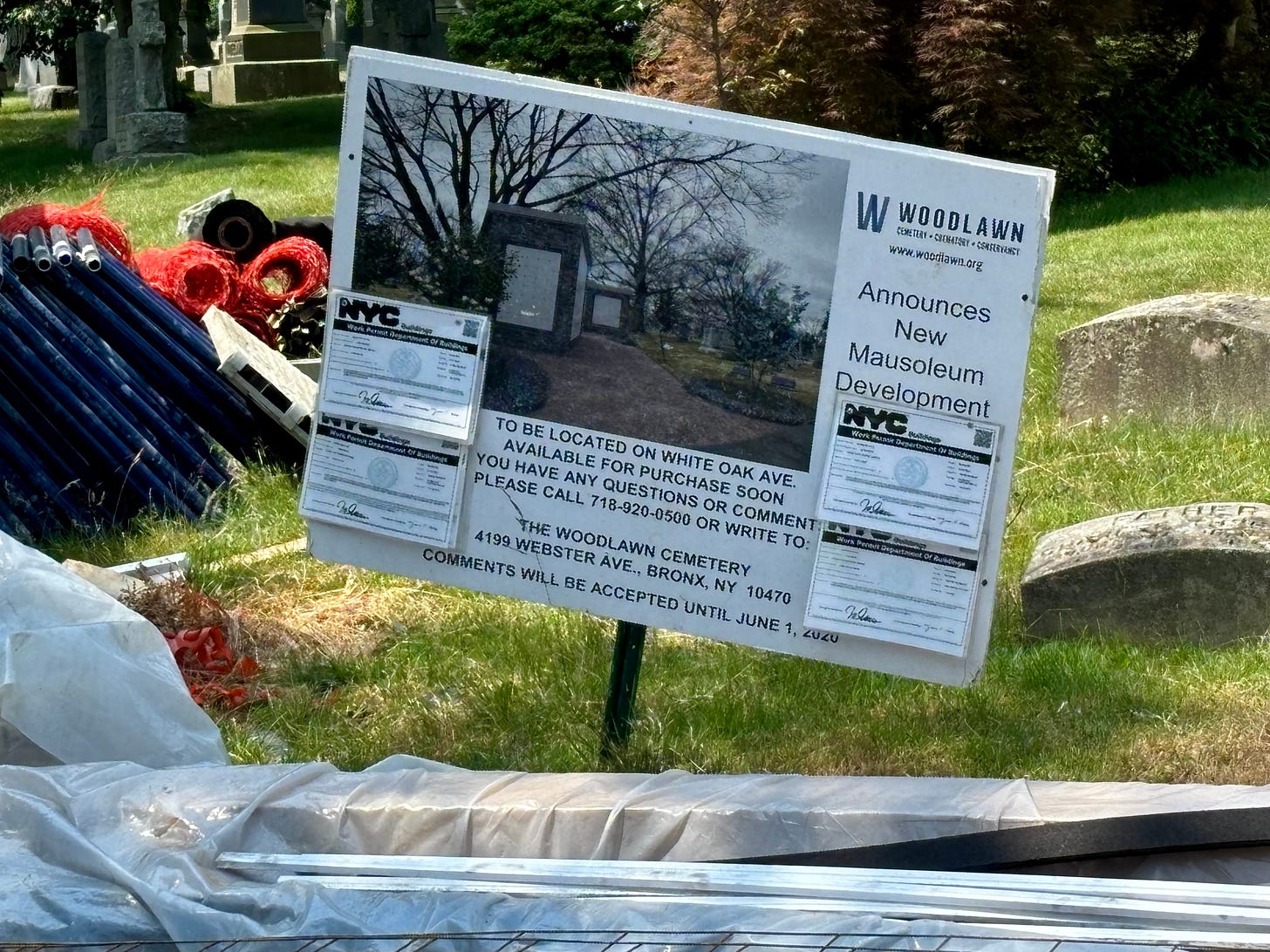 A sign posted amid construction equipment. It reads "Woodlawn Announces New Mausoleum Development." There are work permit forms from the DOB attached.