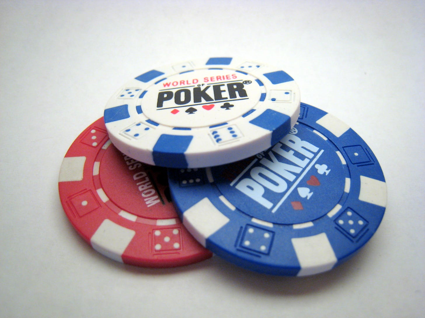 A picture of 3 different coloured poker chips loosely stacked