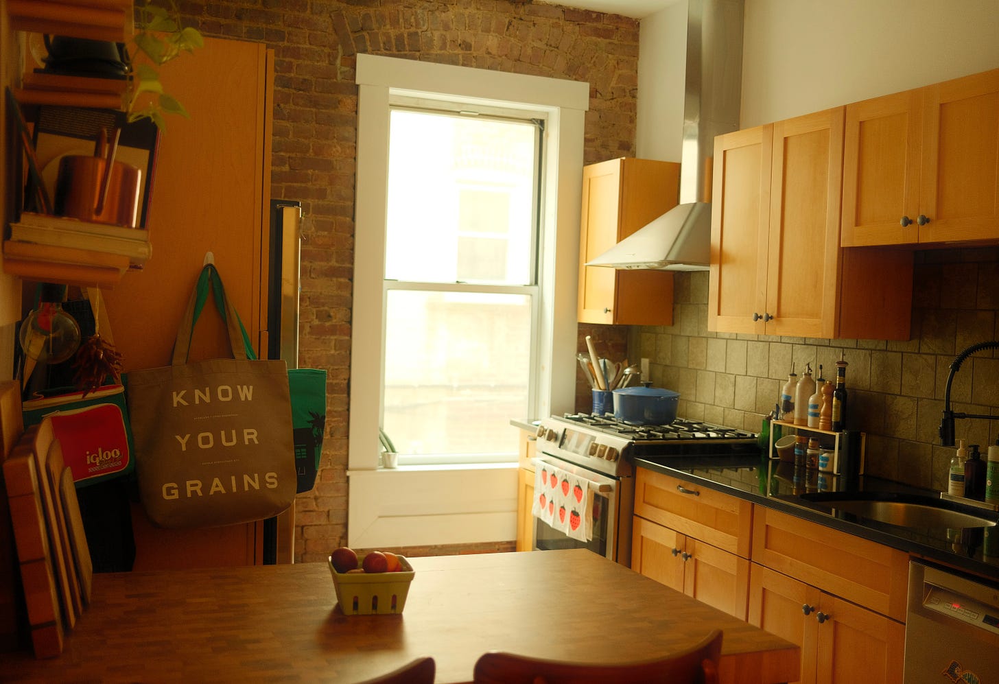 Kitchen with wooden table, bright window and wooden cupboard doors.