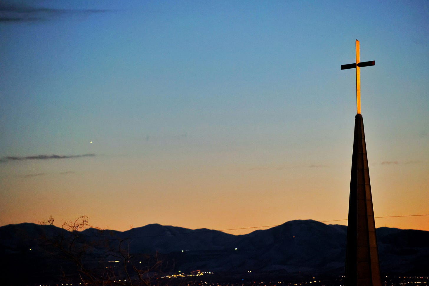 Christian steeple with a cross at sunset