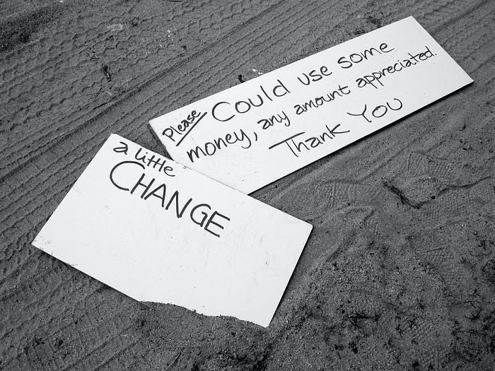 A couple of signs asking for spare change. A couple of signs asking for spare change.