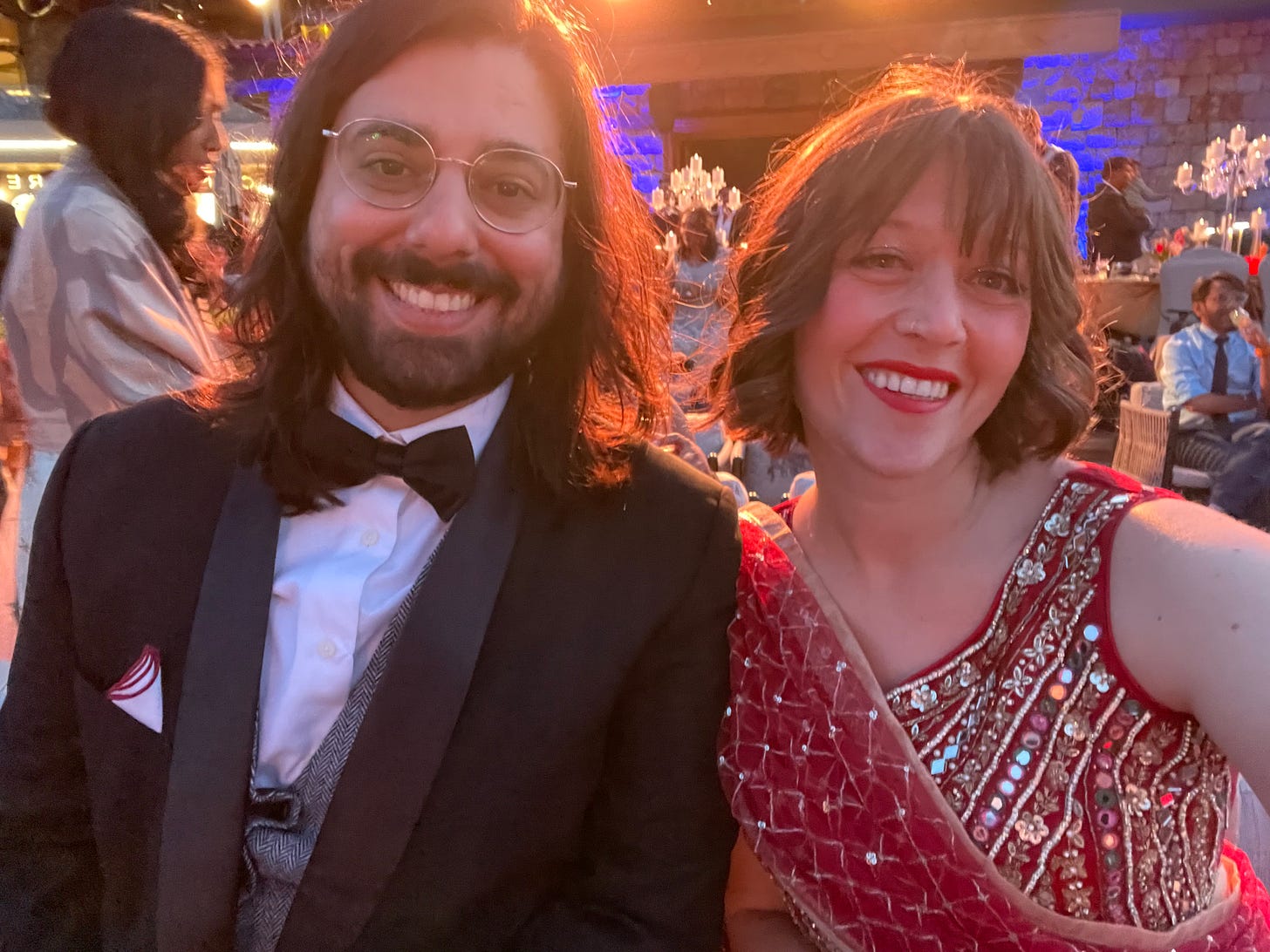 Alex in a tux and Camille in a red lehenga at a wedding in Turkey.