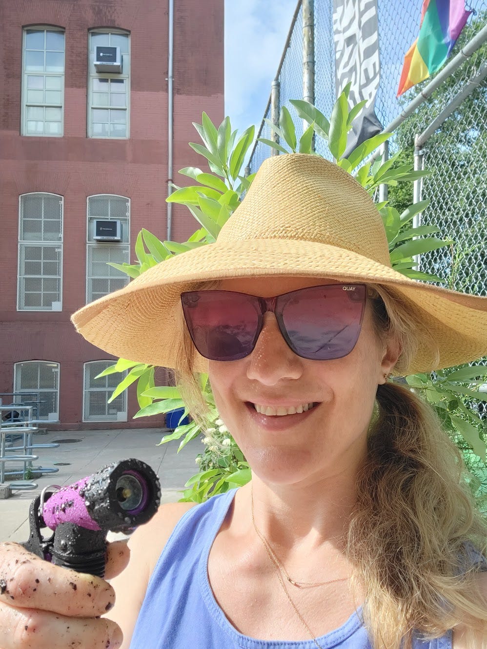 a smiling white woman in a straw hat and sunglasses