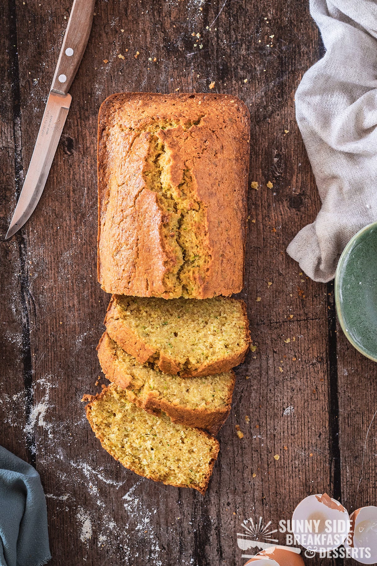 Zucchini cornbread on a wood table, partially sliced.