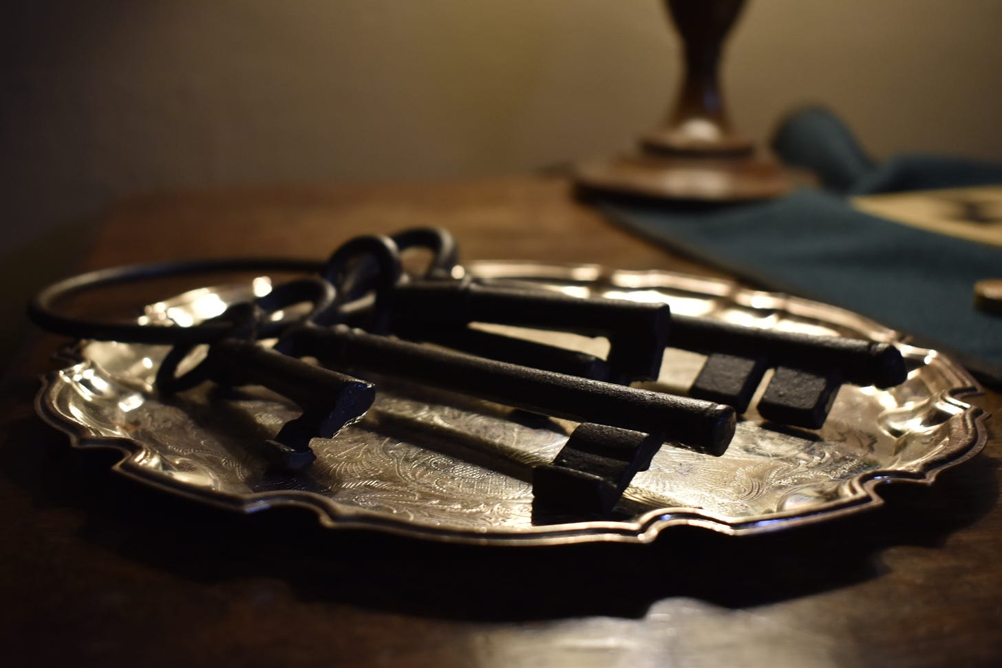Four large iron keys rest on an ornate silver tray