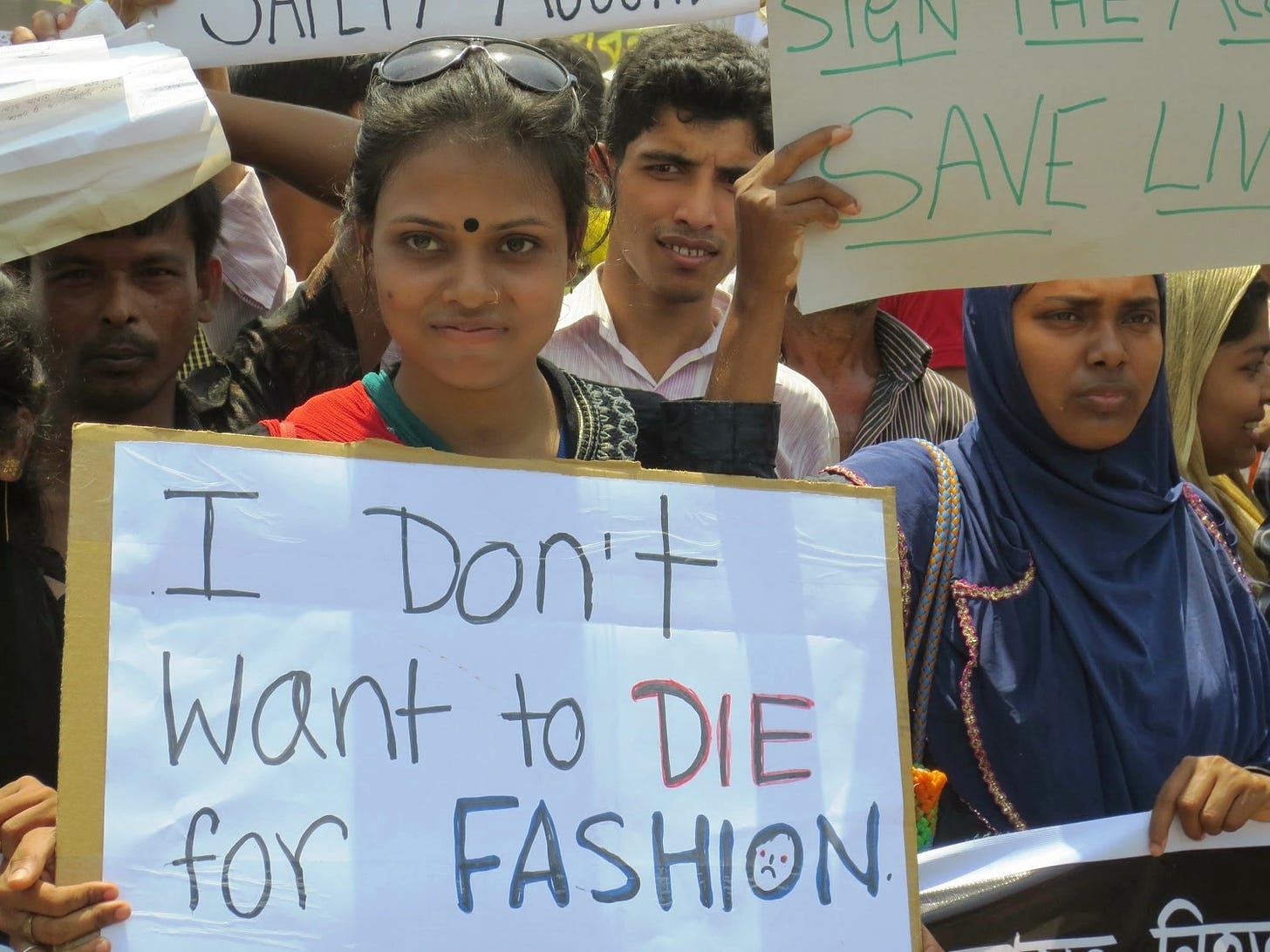 Bangladeshi garment worker holding a sign at a protest: "I don't want to die for fashion".