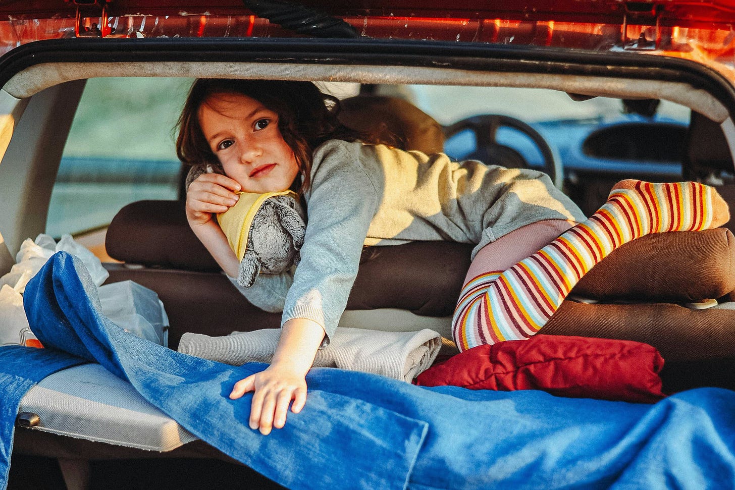 girl on top of stuff packed in an automobile trunk