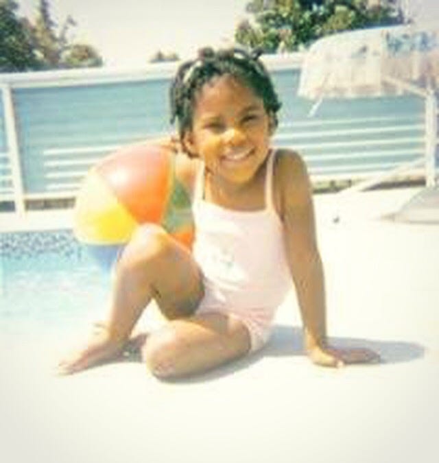 Black girl in a faded photo wearing a pink bathing suit and smiling