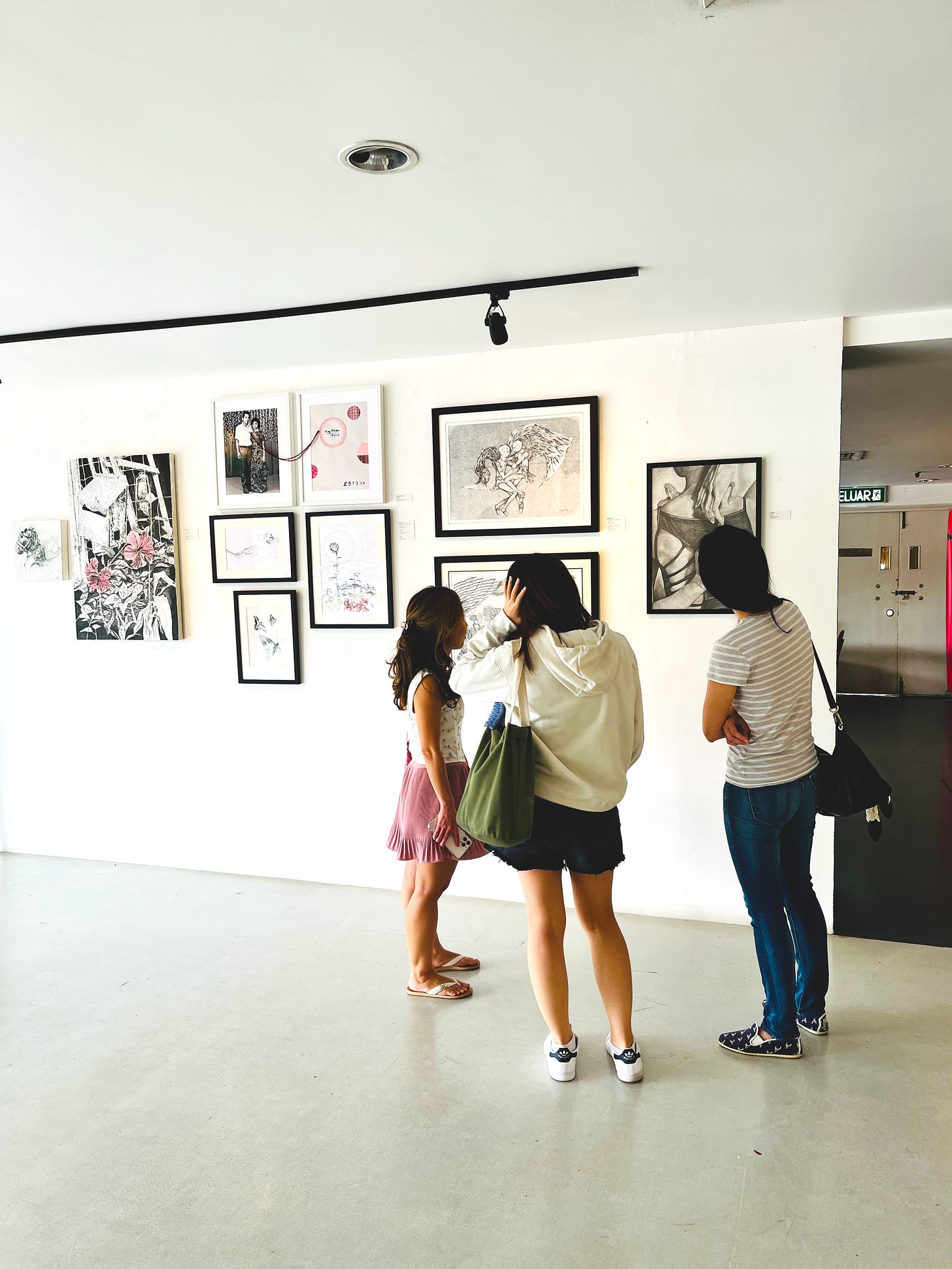 image: a photo of 3 people standing in front of different artworks in the gallery.