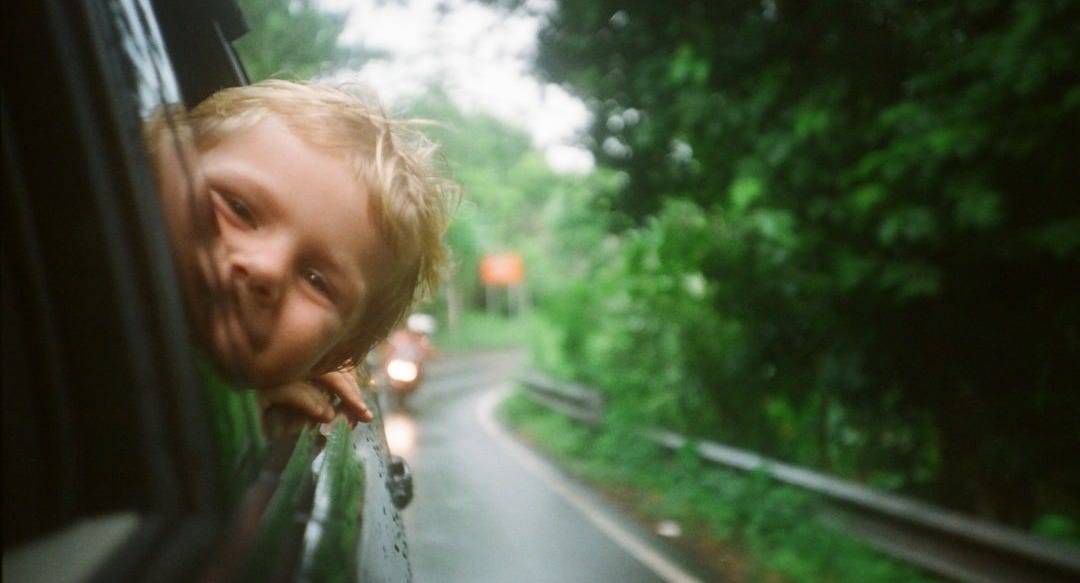 child peeking from vehicle window