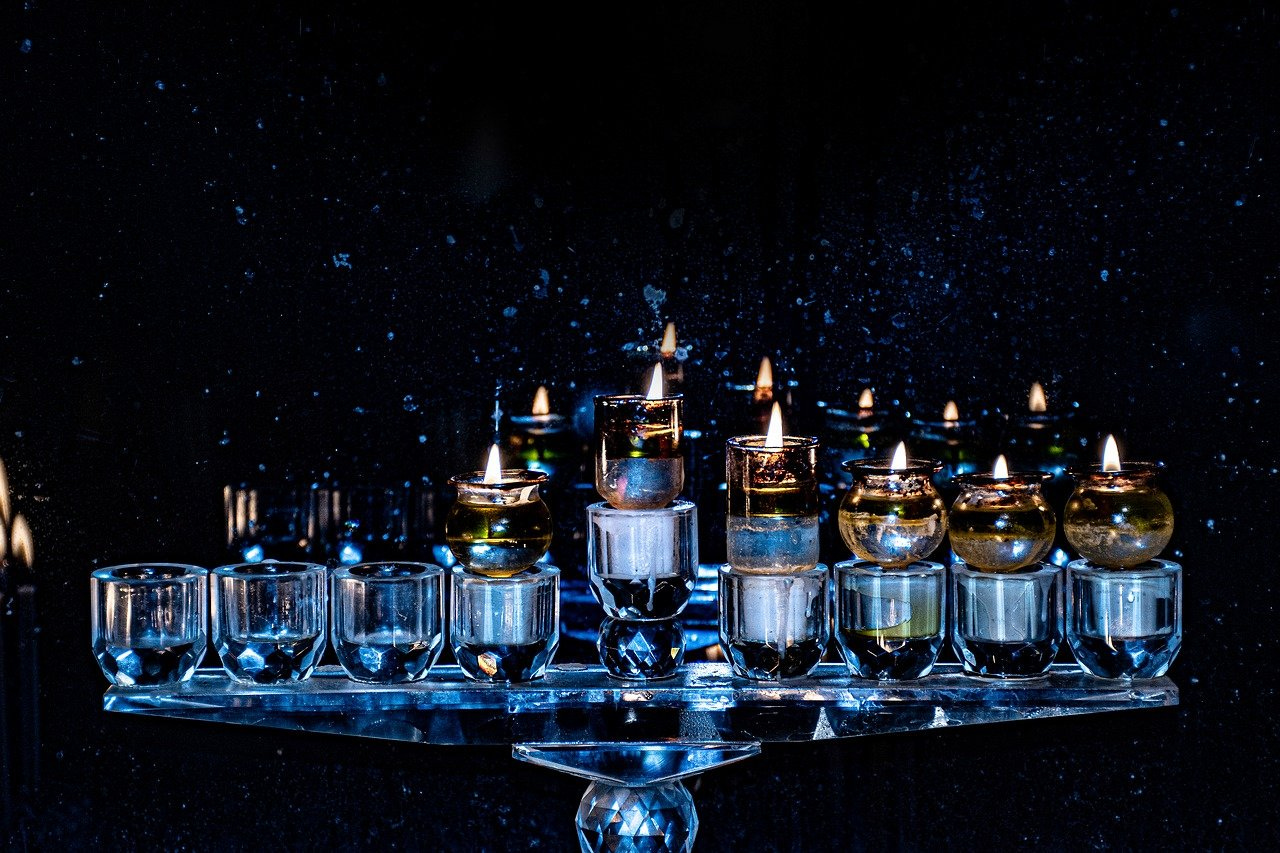 a hanukkah menorah with flames burning set in a dark window