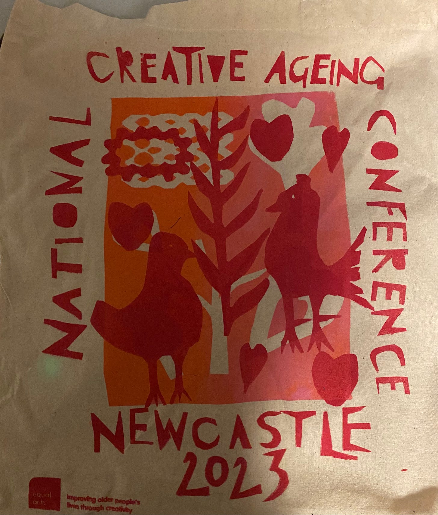 Totebah in red white and orange, woodvutstyle lettering saying Newcastle Creative Aging Conference Newcastle 2023, pictures of birds, hearts and trees