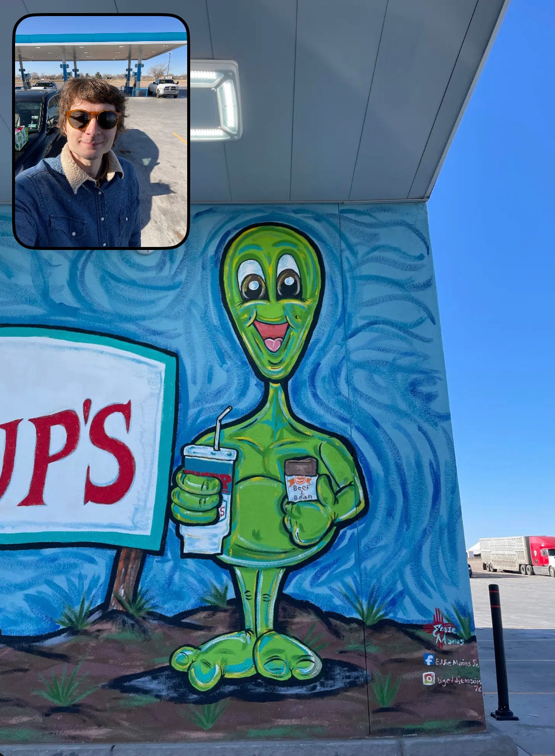 A mural of a smiling, green alien who is holding a soft drink and a bean burrito. An image of me is superimposed in the top left corner. The photo is from the app BeReal.