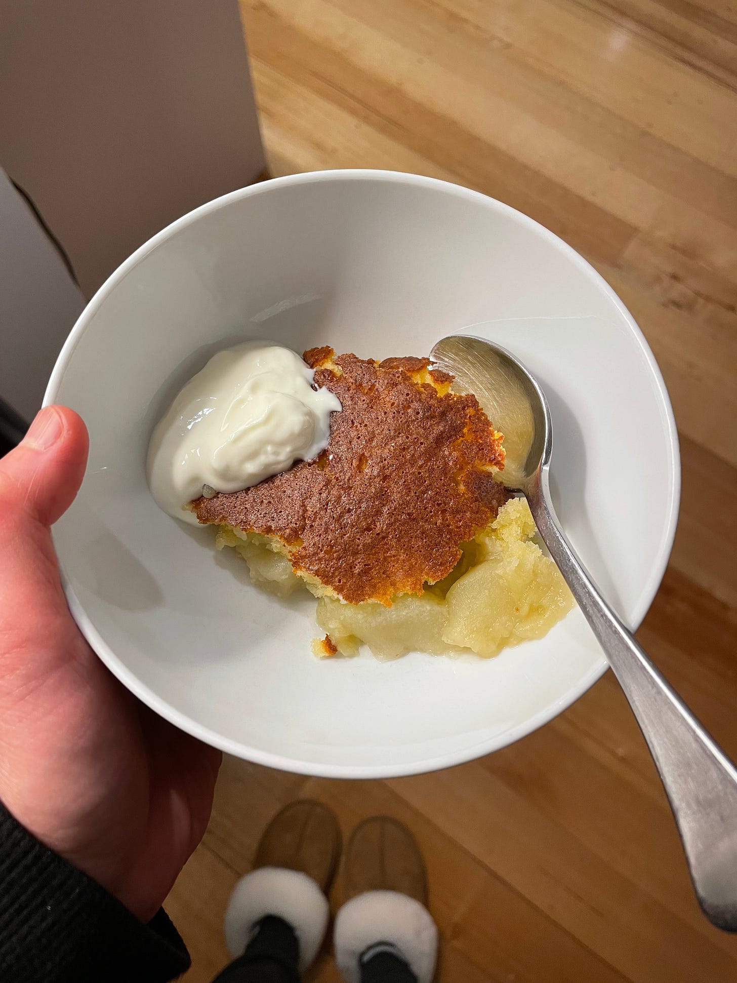 Bowl of apple pudding topped with a sponge-cake top, served with yoghurt.