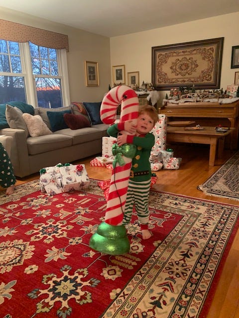a child hugging a lawn ornament candy cane 