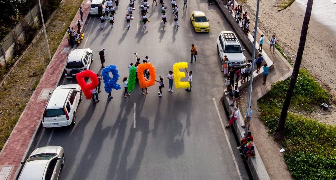 group of person walking on road carrying Pride balloons group of person walking on road carrying Pride balloons