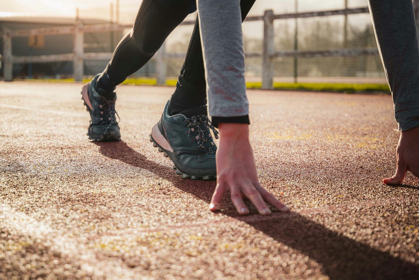 A picture of a runner preparing to begin a race. Their feet are planted and their hands are on the ground. 