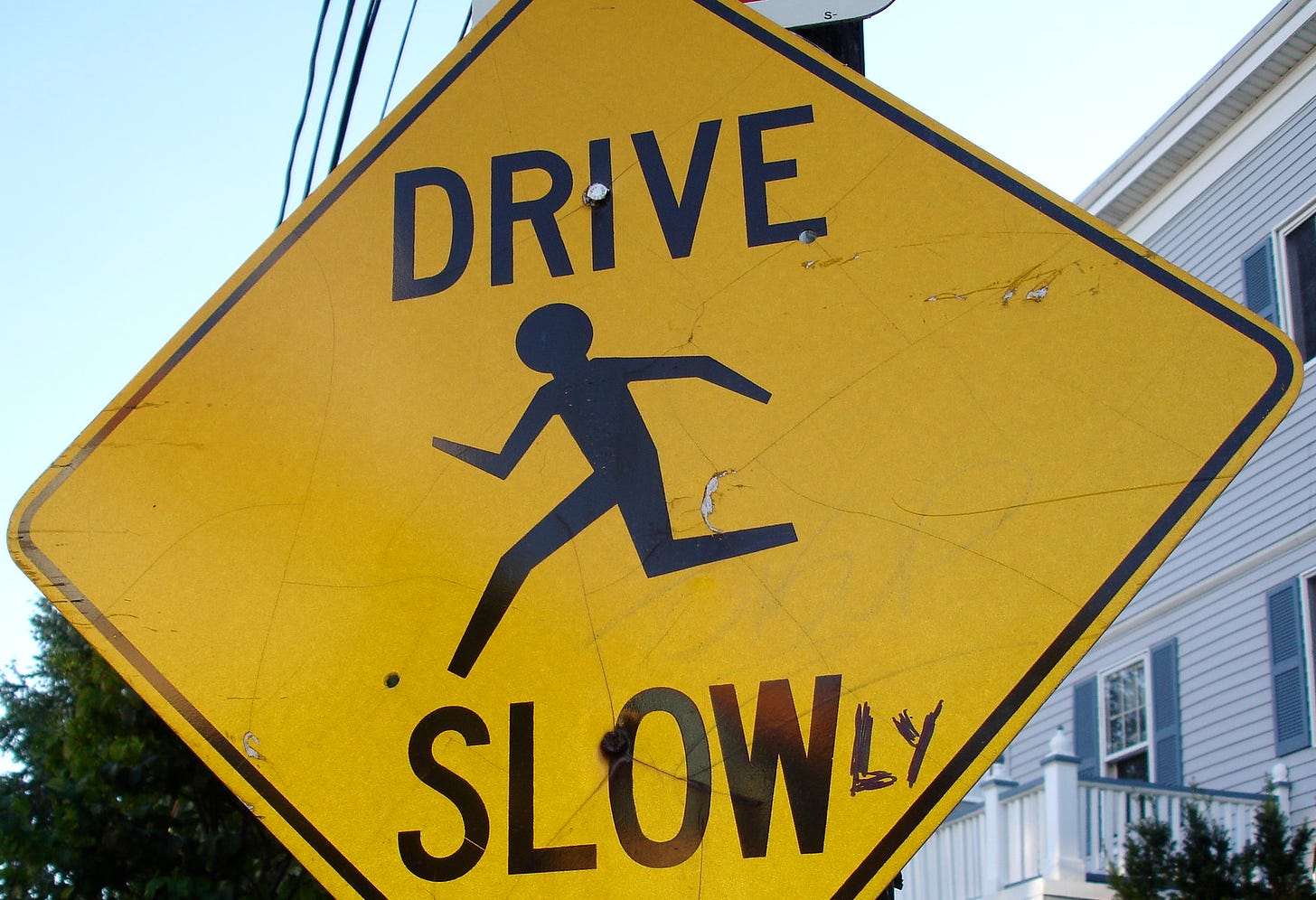A sign that originally read "DRIVE SLOW" corrected to read "DRIVE SLOWLY"