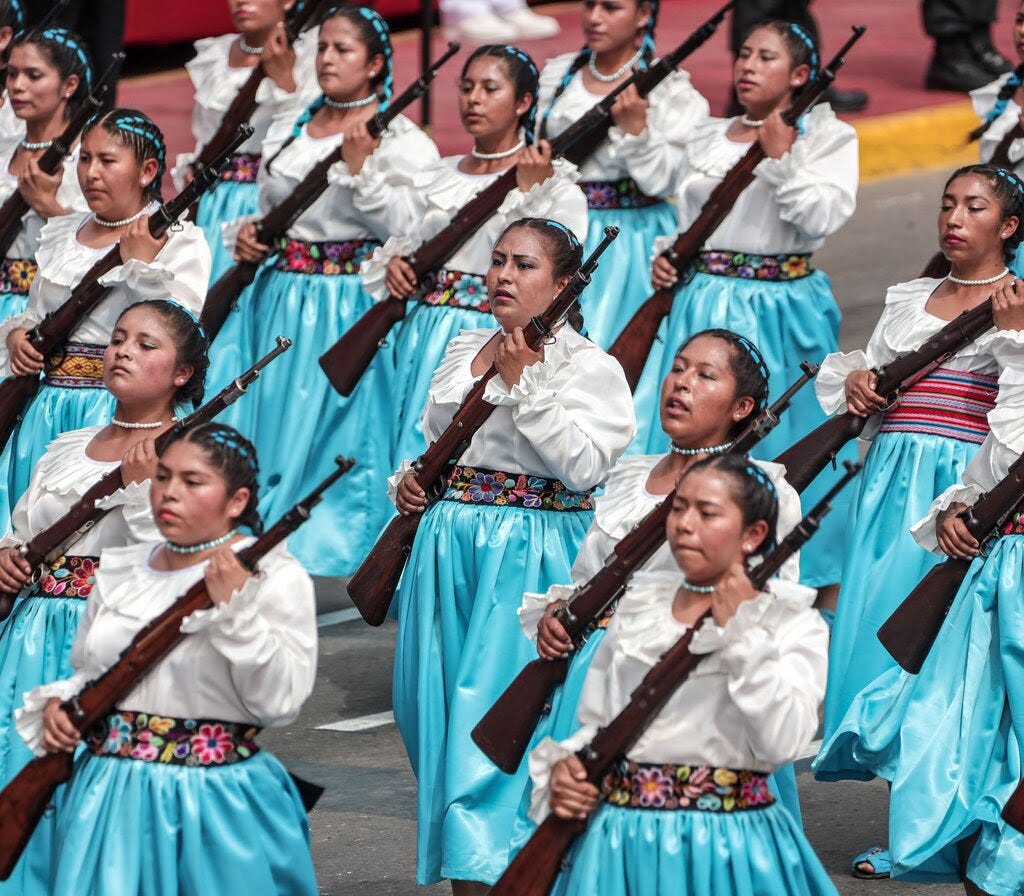 Women carry guns in a parade.