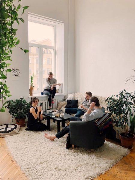 young men women rommates hanging out in white plant filled apartment