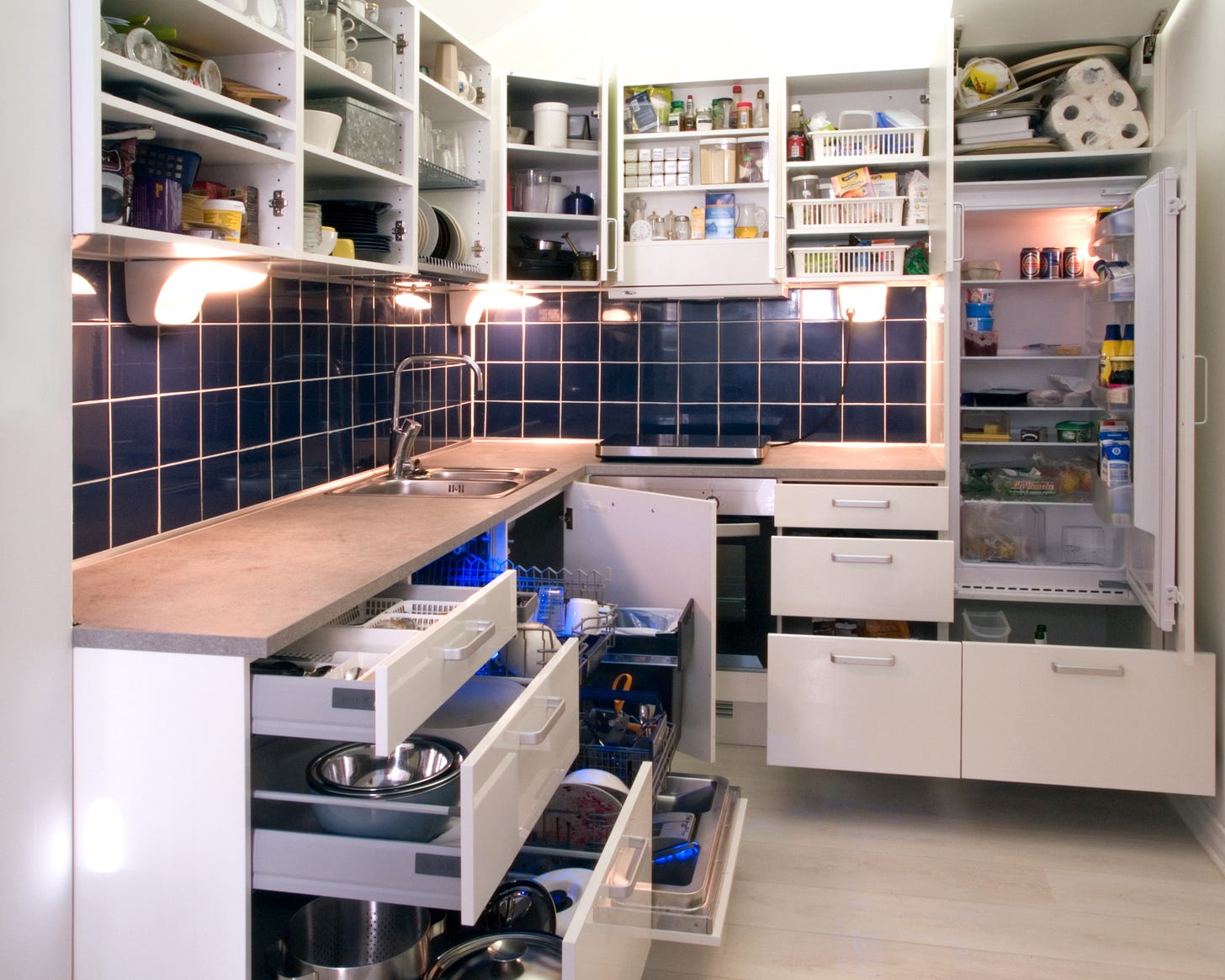 File:White kitchen with cabinet doors and drawers opened or ...