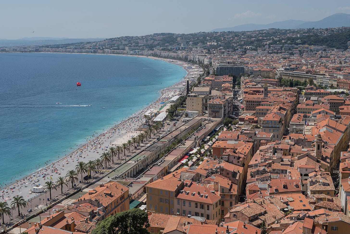 Aerial View of Nice, France – A panoramic view of Nice’s coastline, with the Mediterranean Sea curving along the city’s terracotta rooftops and the Promenade des Anglais stretching along the shore.