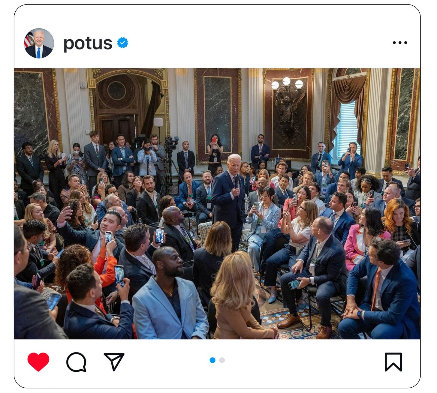 President Biden standing with a microphone surrounded by people at the White House Creator Economy Conference