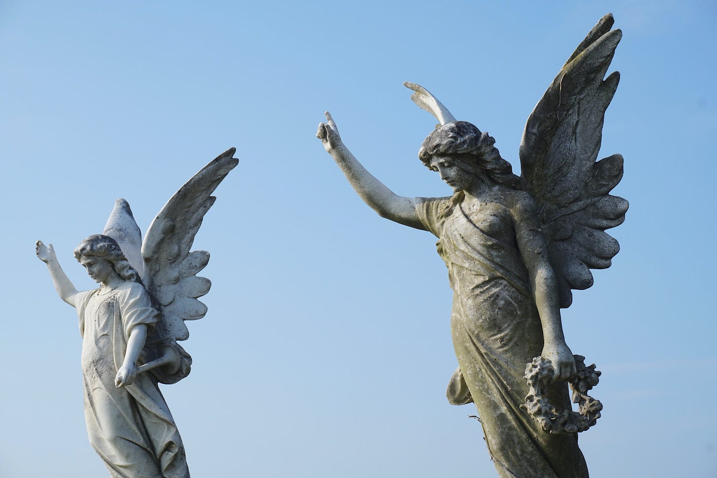 Two angel statues point up to the sky as if motioning to heaven 