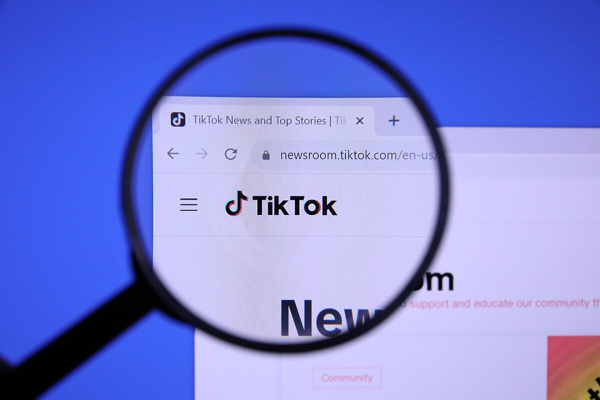 A magnifying glass over the homepage newsroom.tiktok.com/en-us/, showing the TikTok logo