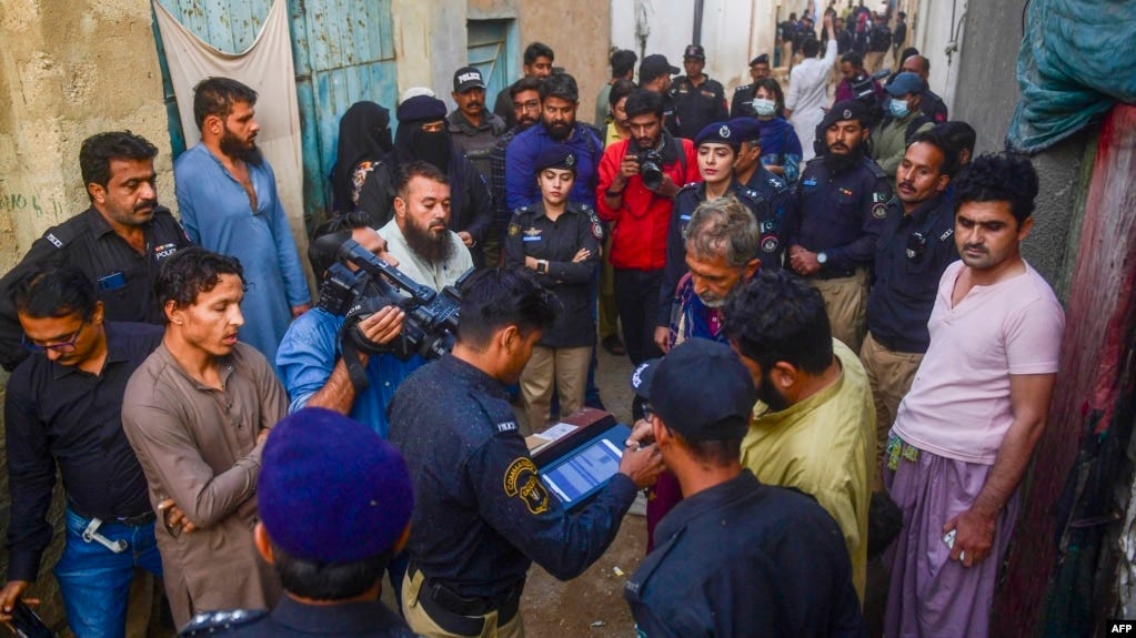 FILE - Police personnel test biometrics of Afghan refugees during a search operation to identify alleged illegal immigrants, on the outskirts of Karachi, Pakistan, Nov. 17, 2023.