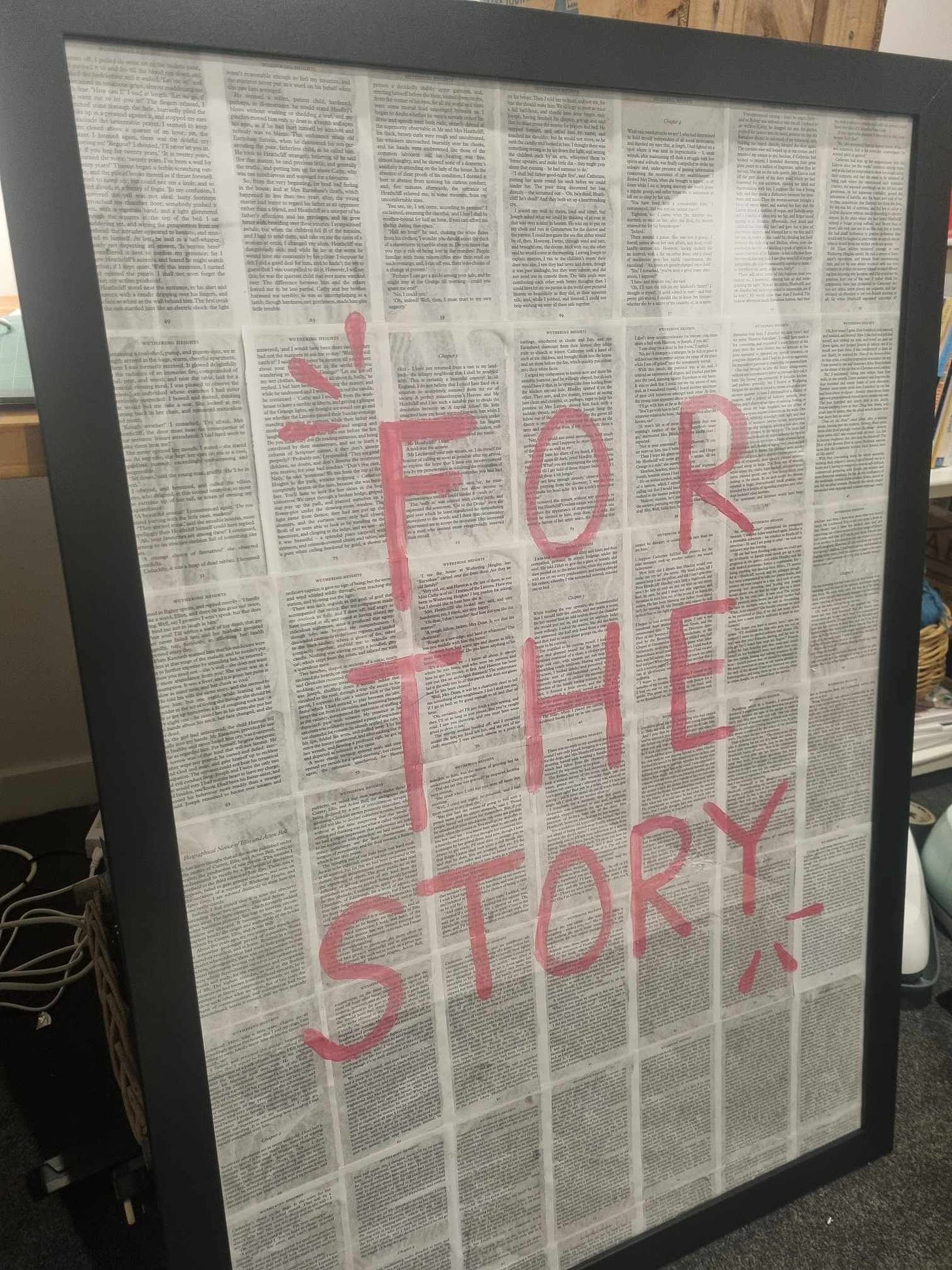 A large black frame with a collage of book pages and the words 'for the story' painted in pink.