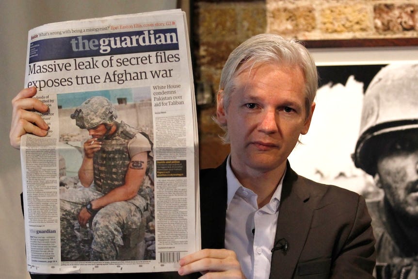 Assange, vu ici avec une apparence beaucoup plus jeune, brandit le journal sur lequel on peut lire qu'une fuite massive de documents secrets révèle la véritable guerre en Afghanistan