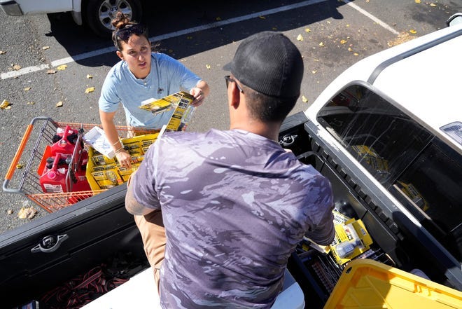 Dustin Akiona, 31, and Marina Sanchez, 28, gather supplies needed for community members in Lahaina on Aug. 12, 2023. Dozens of people are still missing and thousands were displaced after a wind-driven wildfire devastated the town of Lahaina on Aug. 8. Crews are continuing to search for missing people.