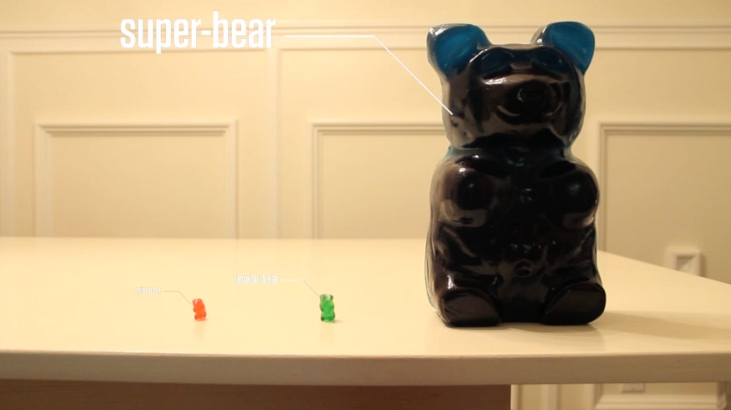 A giant super gummy bear next to regular size bears.