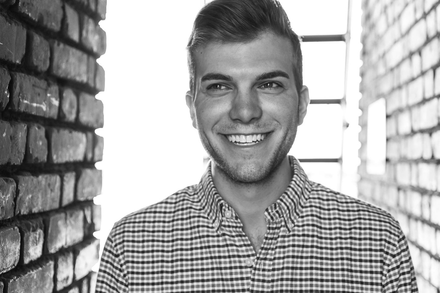 Black and white photo of Jeffrey Wisenbaugh, Director of Social & Content at Meta, standing in front of brick