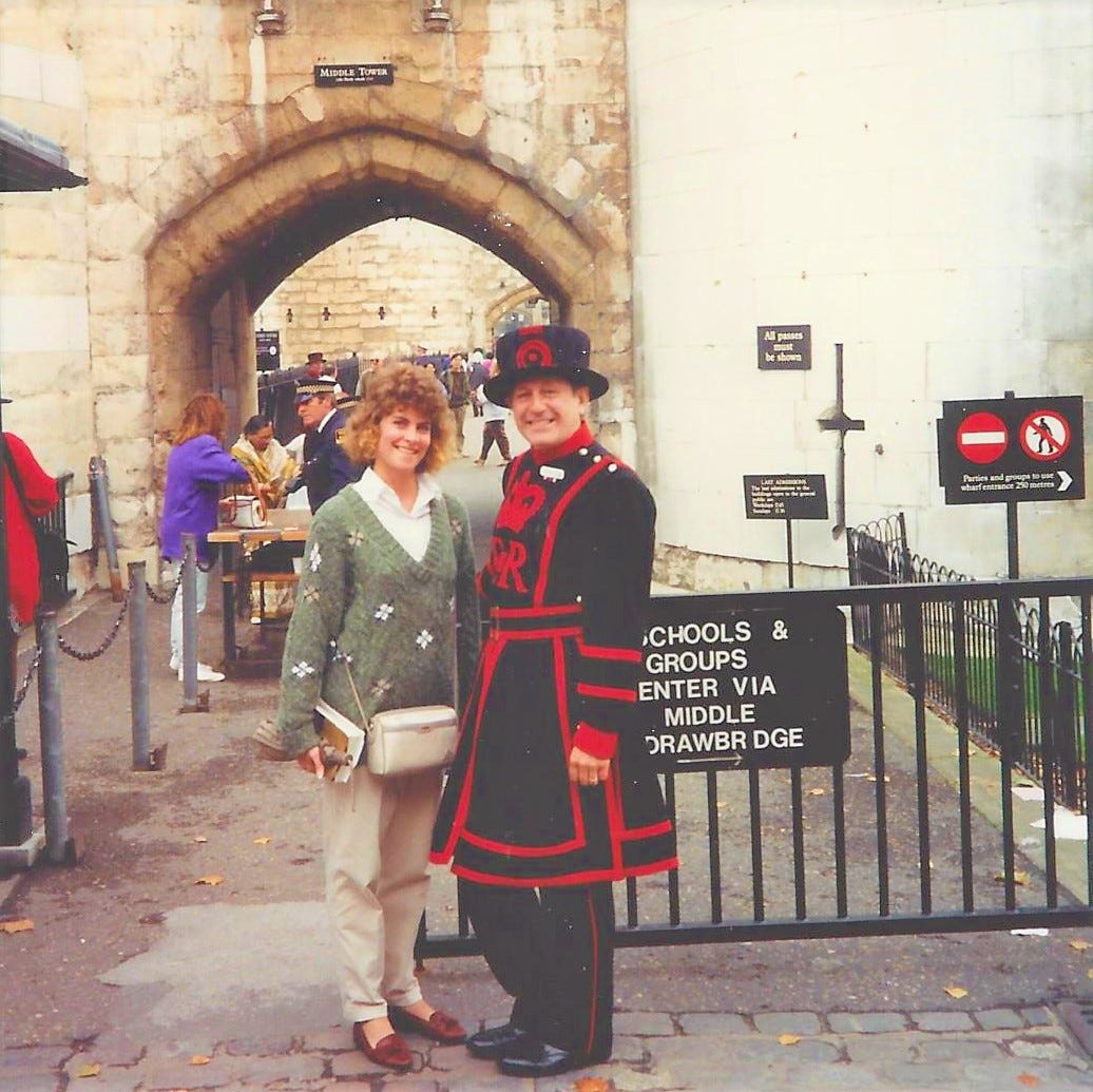 20-something woman stands outside the Tower of London with a Beefeater guard